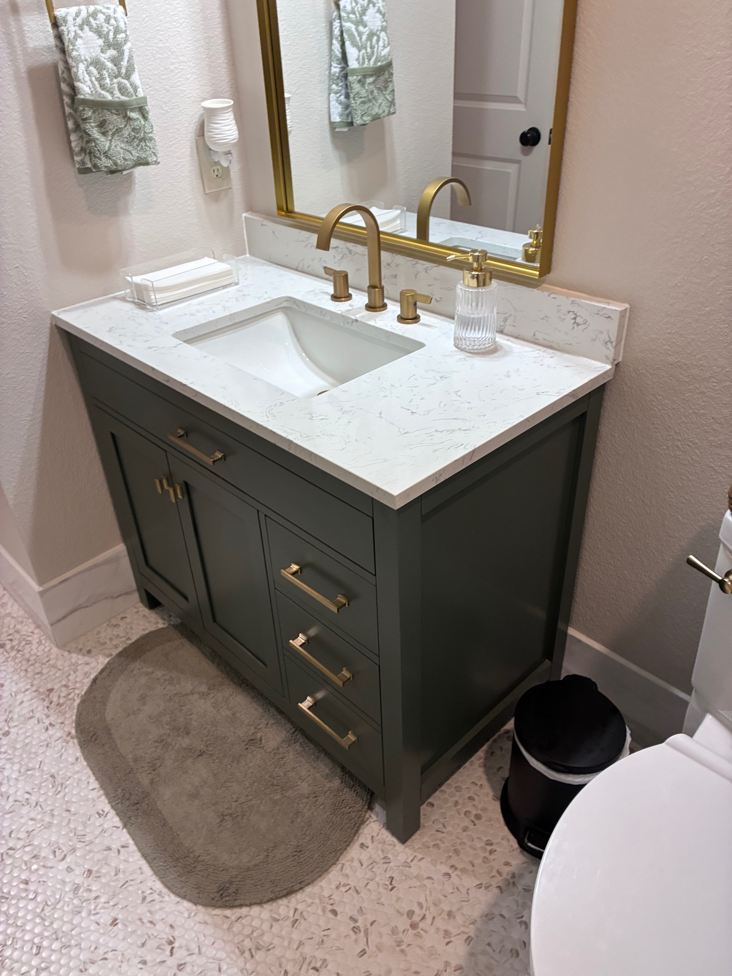 Custom green vanity with quartz countertop and brass fixtures