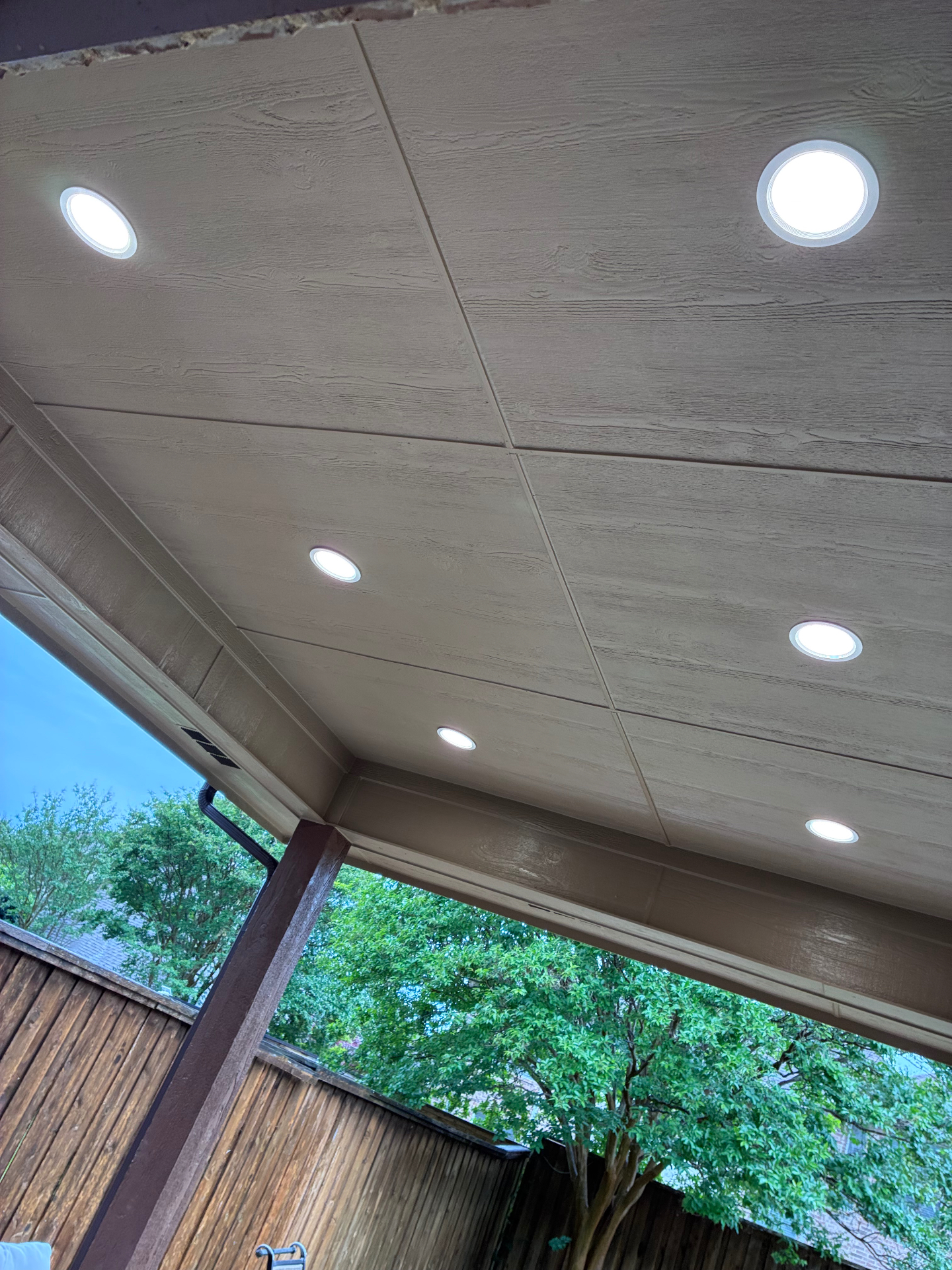 Covered patio ceiling with wood-look planks and recessed lighting