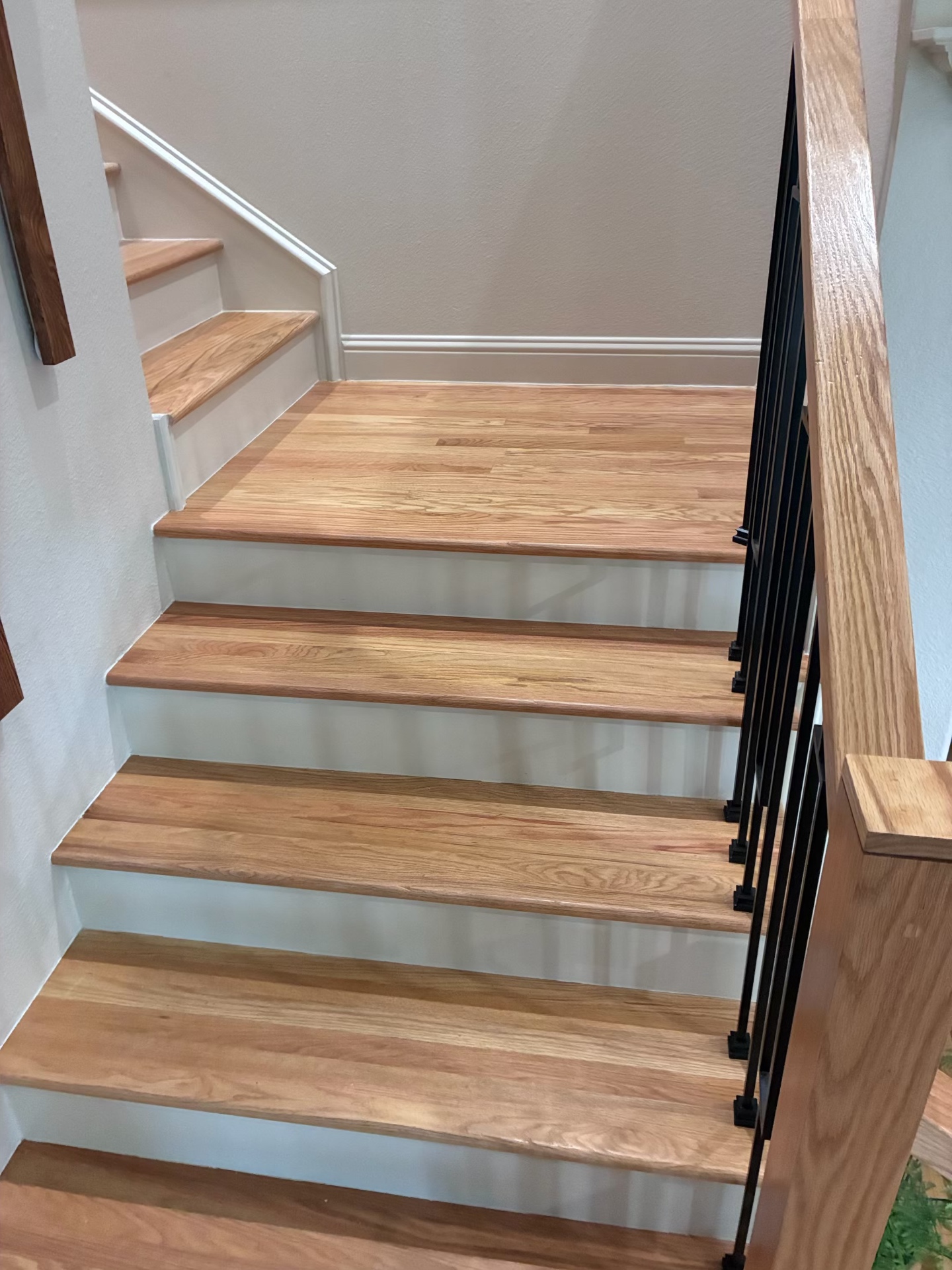 Refinished oak stair treads with modern black metal railing